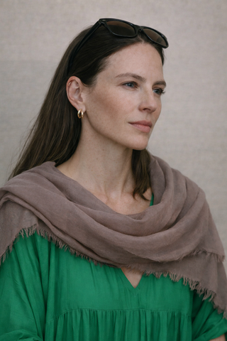 Mdel mit braunen Haaren trägt den MLin Schal in einem schönen Taupe farbenen Ton. Der Schal ist von der schweizer Marke AYRE.