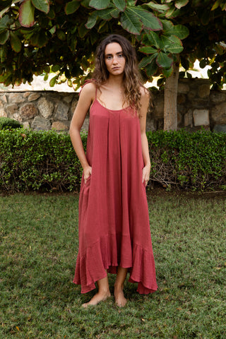 Ein leichtes Sommerkleid aus weichem Baumwoll-Musselin (Double Gauze) in einem warmen Dirt-Red-Ton. ALIX bietet eine fliessende, weit geschnittene Silhouette mit Bindeträgern, Taschen und einem asymmetrischen Volantsaum. Der erdige Rotton bringt Wärme und Tiefe in jeden Sommerlook. Ideal für Reisen, Strandtage und moderne Alltagsmomente. Einheitsgrösse, vielseitig kombinierbar.