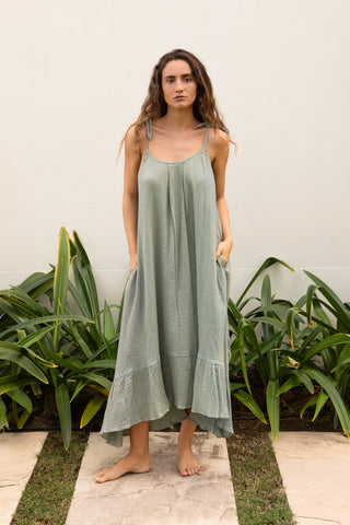 Ein leichtes Sommerkleid aus weichem Baumwoll-Musselin (Double Gauze) in einem ruhigen Seagrass-Petrolton. ALIX bietet eine fliessende, weit geschnittene Silhouette mit Bindeträgern, Taschen und einem asymmetrischen Volantsaum. Weich, atmungsaktiv und vielseitig kombinierbar – ideal für Sommer, Reisen und entspannte Alltagslooks. Einheitsgrösse.