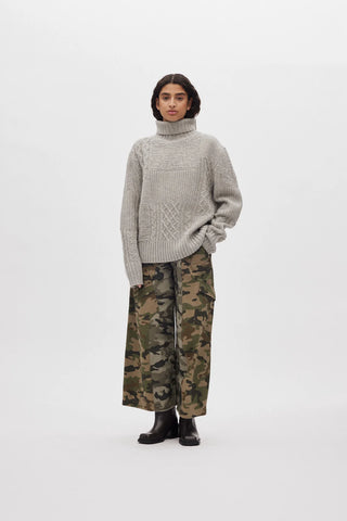 Model trägt eine Camouflage Hose und einen Rollkragen Strickpullover mit verschiedenen Mustern reingestrickt in der Farbe Grey Melange.