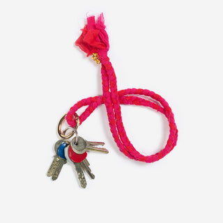 pink roter keychain der marke ayre aus geflochtenten baumwoll reststoffen der kollektion hier mit einem goldenen karabiner an einem schlüsselringe befestigt