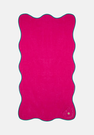 man sieht das pinke Strandtuch der griechischen Marke Sorbet Island. Mit der Wellenform am Rand entlang des Tuches. Sehr frisch.