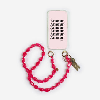 der bonbon keychain der marke ayre an einem handycover befestigt in der farbe berry