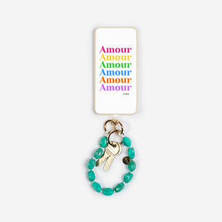 der bonbon keychain der marke ayre in der farbe tuqrquois an einer handyhülle befestigt mit einer schönen rainbow amour illustration darauf