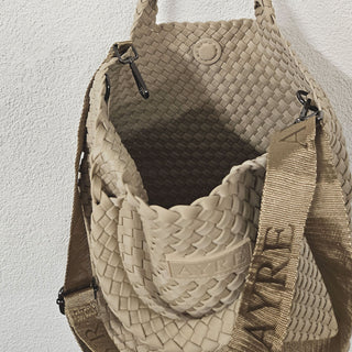 Man sieht in die Cabane Tasche des Schweizer Labels AYRE. Die Tasche ist geflochten aus robustem Neopren, mit einem langen Schulterriemen. Sie ist in der Farbe Powder.