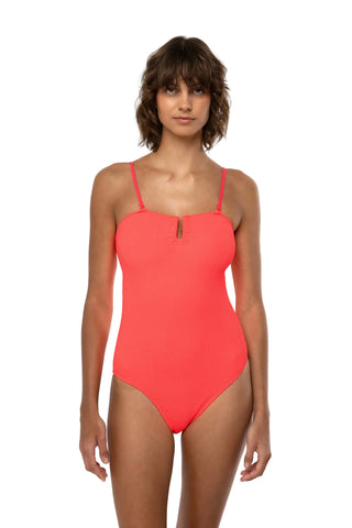 Model trägt Badeanzug der griechischen Marke SORBET ISLAND. Aus einem crinkle Material das man kennt aus den 80er Jahren. Passt sich jedem Körper an. Hier in der Farbe strawberry neon, ein leuchtendes Orange/Pink.  