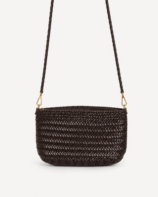 Man sieht die geflochtene Ledertasche CROISETTE der schweizer Marke AYRE. Eine Pochette Bag, die man dank den goldenen Karabinern mit dem geflochtenen Henkel auch Crossbody tragen kann. 