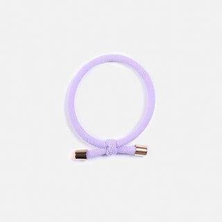 Lila farbenes Haargummi der Schweizer Marke AYRE. Es ist ein sportlich elegantes Haargummi mit einem coolen Knopf und goldenen Enden als Abschluss, elegant und sportlich zugleich.