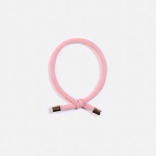 Das Haargummi in oldrose mit dem lässigen Knoten mit den goldenen Details am Ende. Der Schweizer Marke AYRE.