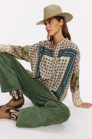 Man sieht eine coole Frau sitzend, mit einem wunderschönen bestickten und bedruckten Seidenhemd der französischen Marke Stella Forest. Hier erhältlich im Webshop von AYRE.