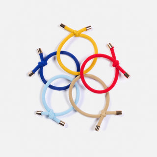 man sieht 5 Haargummis mit dem Namen FLIP der Schweizer Marke AYRE: Die Haarummis haben einen Knoten der sehr edel wirkt, dank den goldenen Abschlüssen. Die Farben sind rot, beige, skyblue, royal blue und mustard.