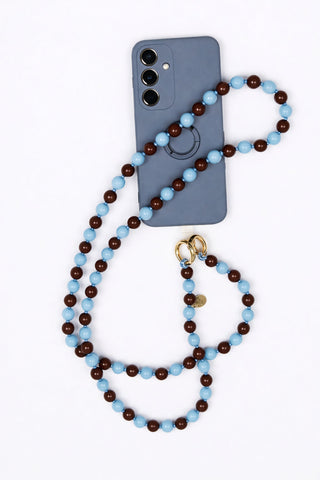 man sieht ein Handy und eine dazugehörige Handykette der schweizer Marke AYRE. Sie ist aus Holzperlen und abwechselnd hellblau und braun.