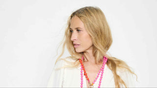man sieht ein blondes Model, sie trägt die bunten Handyketten und Schlüsselanhänger um den Hals, in den farben pink und rot, der schweizer Marke AYRE.