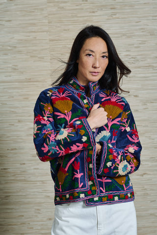 Model Vivienne trägt eine blaue bestickte Samtjacke. Die floralen Stickereien sind sehr bunt, erinnern an Korallen, in den Farben pink, rot, hellblau, senfgelb und weiss.