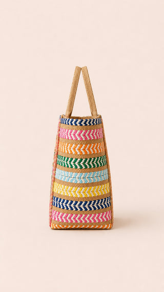 Man sieht die grosse Strandtasche LAMAR der schweizer Marke AYRE von der Seite. Viele Farben gemixt mit dem Stroh. Eine wunderbare Tasche für einen Tag am Wasser.