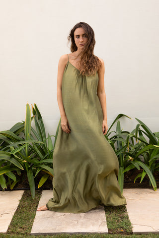 Frau trägt ein olive farbenes Trägerkleid der schweizer Marke AYRE. Es heisst Lexane und ist bodenlang. Sehr elegant.