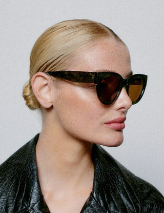 Blondes Model trägt die Lilly Sonnenbrille in grün. Eine grosse klassische Sonnenbrille