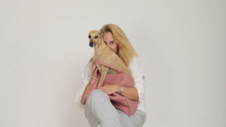 Man sieht Sybille mit dem Hund Bruma, in einer Maison Tasche sitzend, auf Sybilles Schoss. Die Maison Tasche ist oldrose, heisst Maison, und ist aus Neopren. Von der schweizer Marke AYRE.
