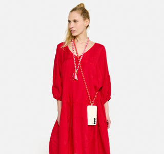 Model Sandra trägt das MAUDE Kleid der schweizer Marke AYRE und um den Hals und die Schultern je einen Keychain und eine Handykette ebenfalls der schweizer Marke AYRE. Die Handykette ist aus von Hand zusammengeknüpften Holzkugeln. Und der aus Stoff gezöpfelte Keychain ist um den Hals aus Stoffen der Kleiderkollektion verwertet. 