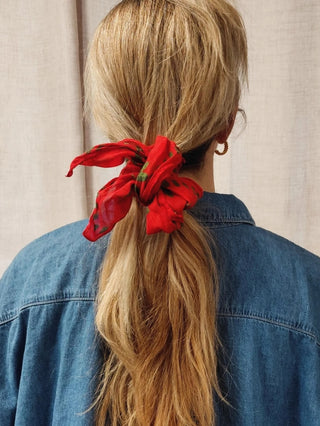 Man sieht das MIMI Bandana / Foulard der schweizer Marke AYRE hier als Band fürs Haar genutzt. Ein Pferdeschwanz wird durch das rote Foulard zusammengehalten.