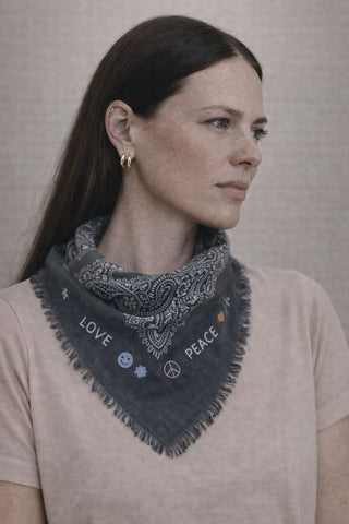 Ein Model trögt den lustigen und schönen Monsterli Schal des schweizer Labels AYRE. Ein Wolle/Seide Schal mit Paisley Muster und aussen herum lustige und positive Stickereien, wie Happiness, Rainbow, Peace usw. 