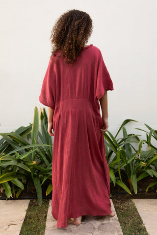 Model zeigt von hinten das SORBONNE Kleid der schweizer Marke AYRE. Ein bodenlanges Kleid mit einem Bund um die Taille. Locker sitzend und hier in der Farbe Berry, ein warmer Beerenton.