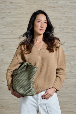 Vivienne trägt den camello farbenen Kaschmirpulli VINCE, der Schweizer Marke AYRE. Ein klassischer Kaschmirpulli mit einem V-Neck. Unter dem Arm trägt sie noch die MAISON Tasche, ebenso von der Marke AYRE, aus robustem und edlem Neopren. 